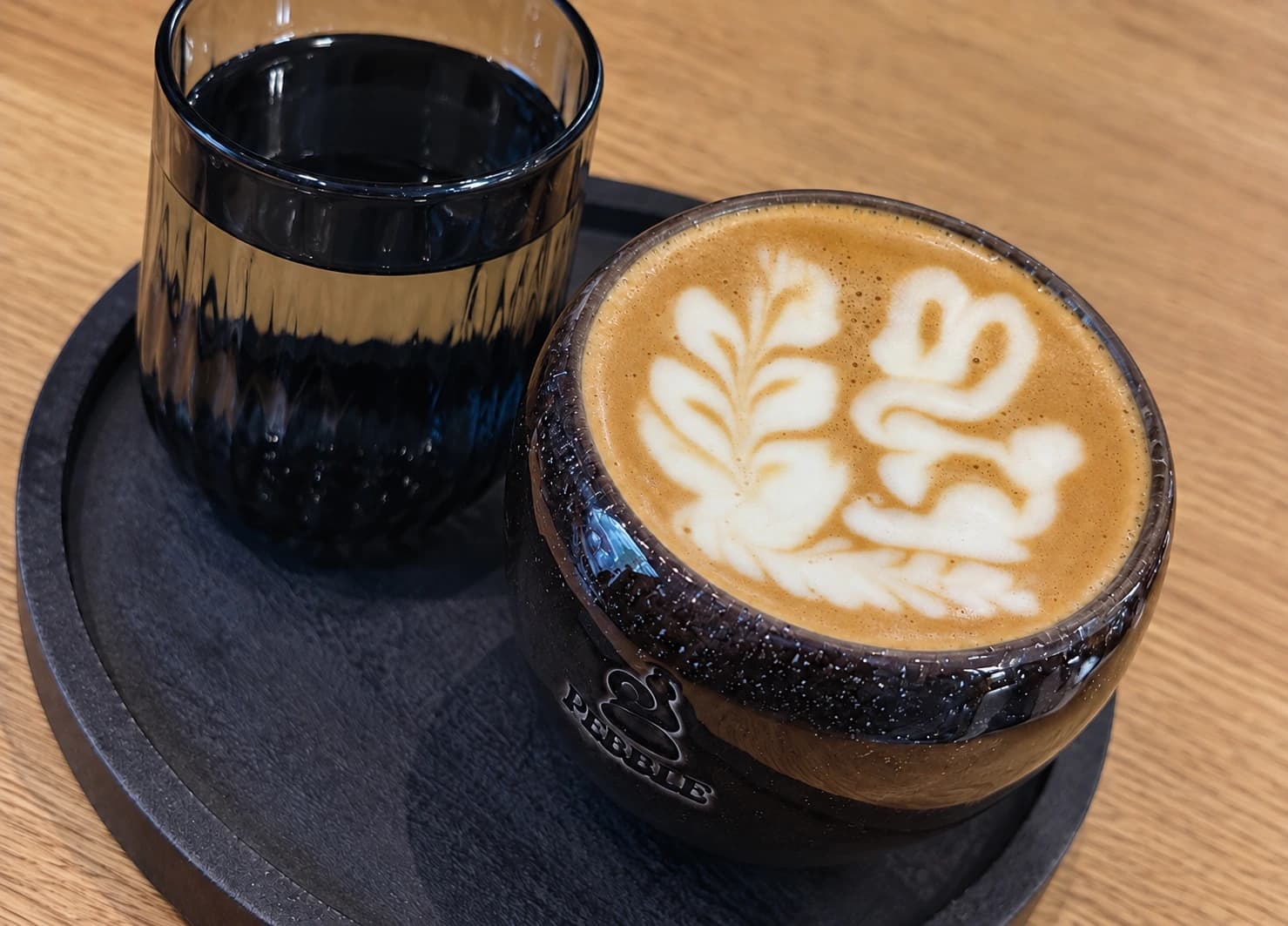 Bunny latte art in a PEBBLE ceramic cup, with water on a dark tray